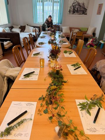Tischdeko aus Efeu, Hagebutten und Moos zwischen den Rezeptbögen, im Hintergrund wird fotografiert